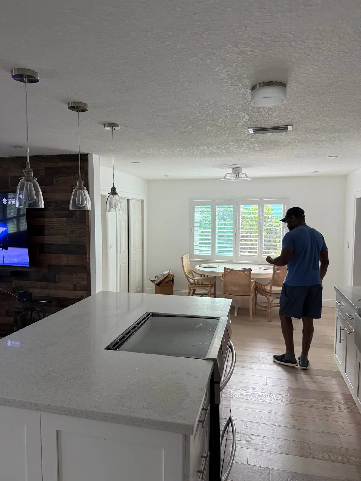 A technician is standing in a modern kitchen with a cooktop on an island counter