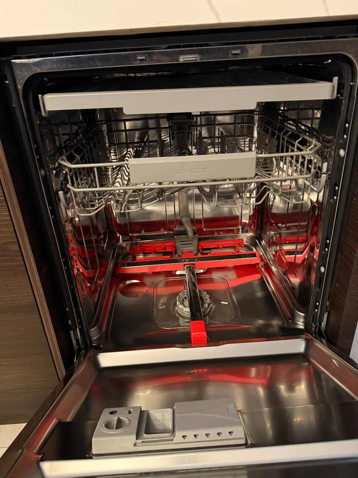 A Dacor dishwasher with its door open, showing the clean interior racks and wash arms