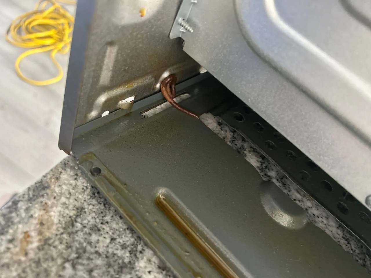 The internal wiring and insulation of an oven on a granite countertop