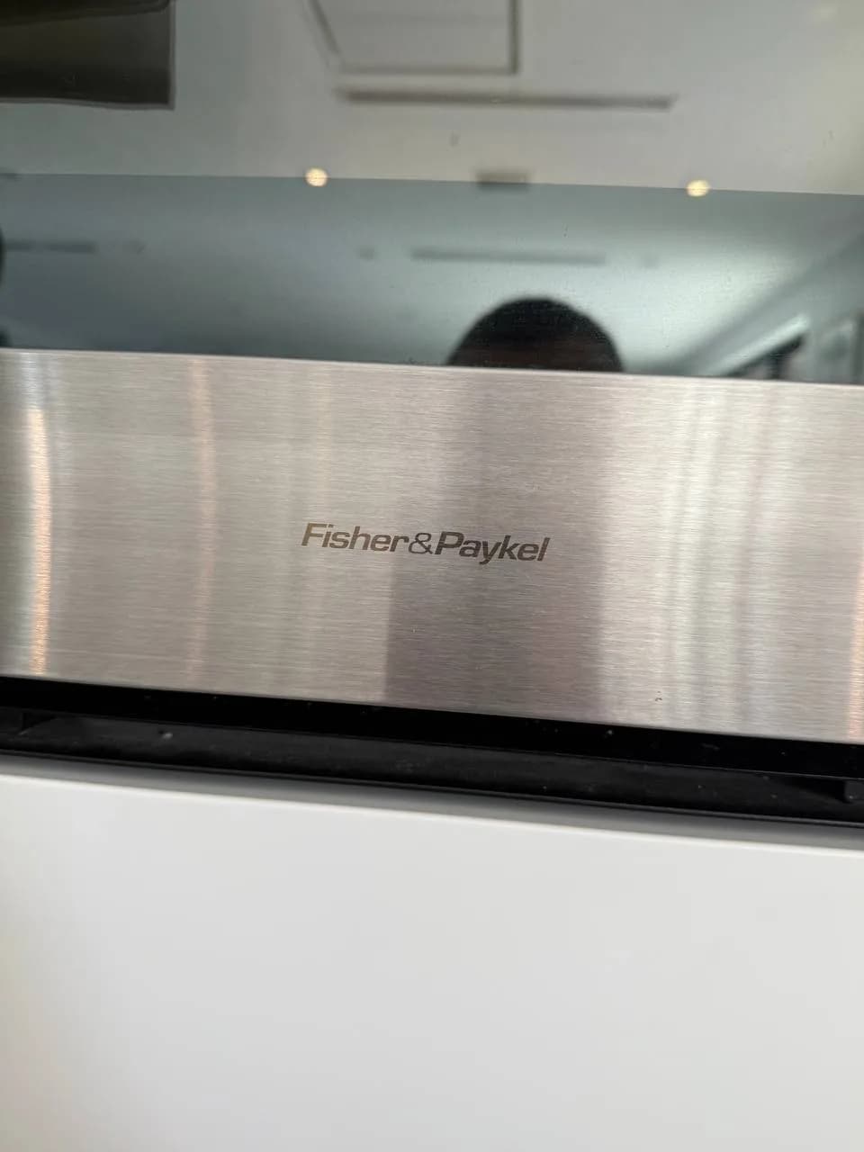 The Fisher & Paykel brand name on a stainless steel appliance surface, likely a dishwasher