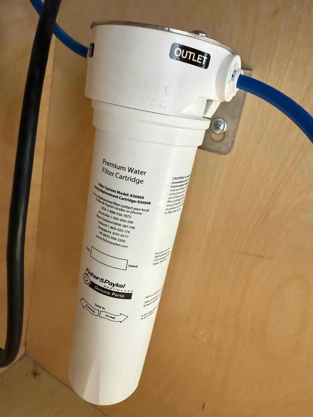 A Fisher & Paykel Premium Water Filter Cartridge attached to a light wooden surface