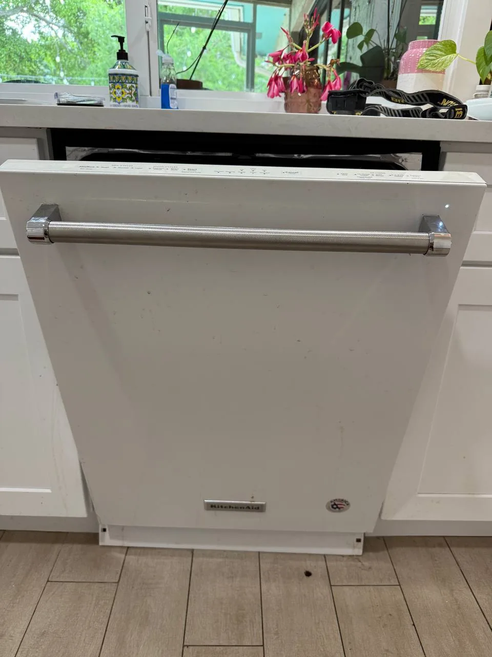 A white KitchenAid dishwasher is installed in a kitchen setting