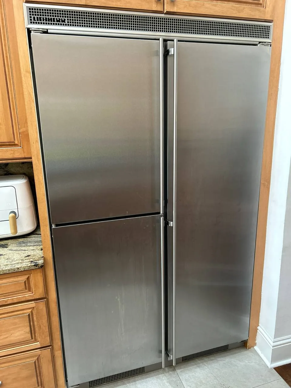A stainless steel Liebherr refrigerator with two doors in a kitchen setting with wooden cabinets