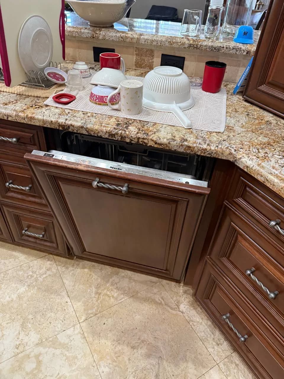 The an open Miele dishwasher installed in a kitchen with wooden cabinets