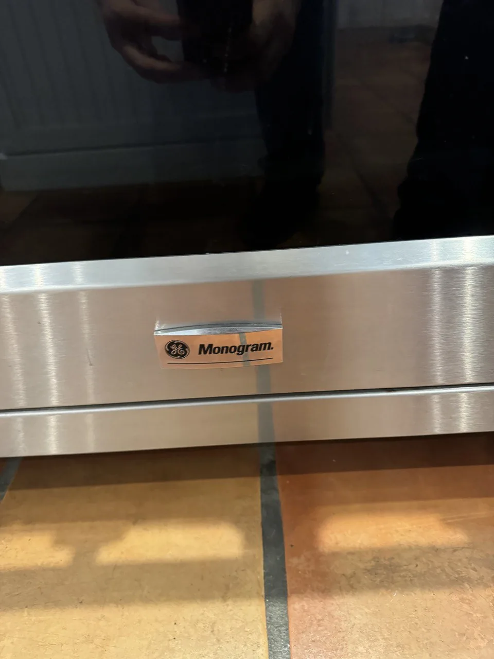 A close-up of a GE Monogram oven with a reflection of the technician in the door