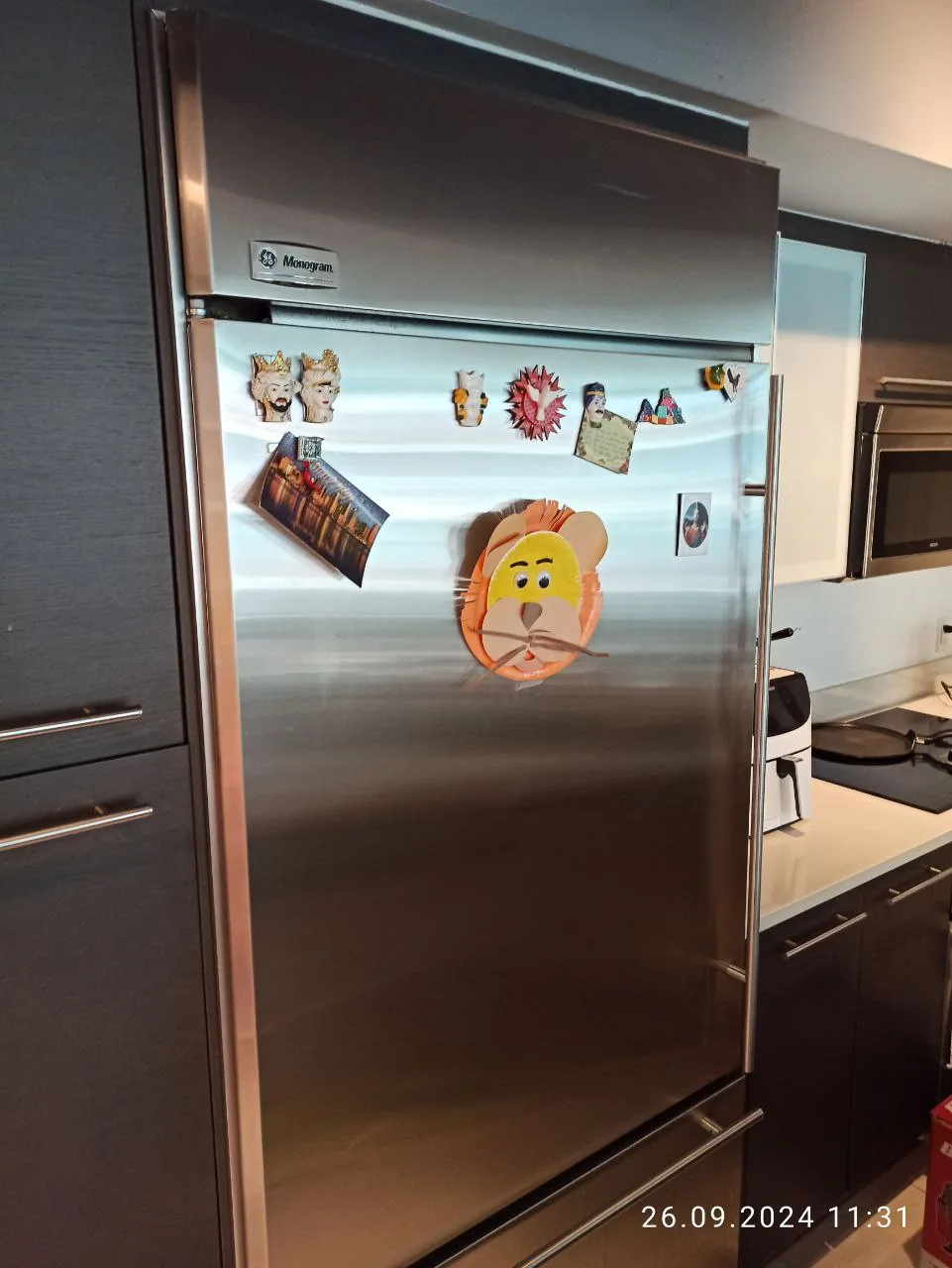 GE Monogram refrigerator service: a stainless steel Monogram refrigerator with magnets on its door in a kitchen setting