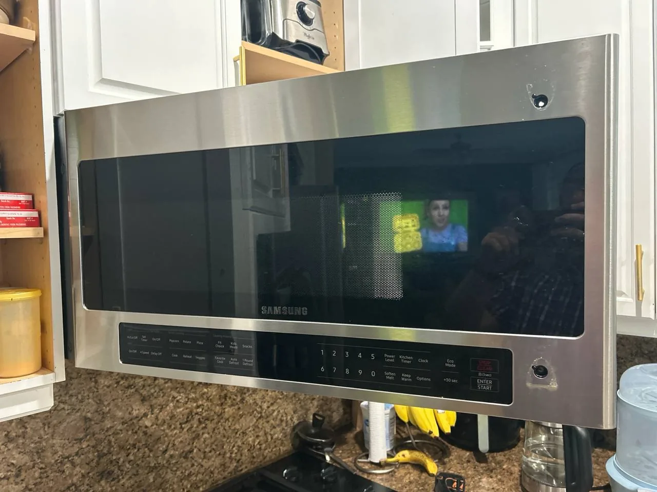 A stainless steel Samsung microwave is installed above a countertop in a kitchen