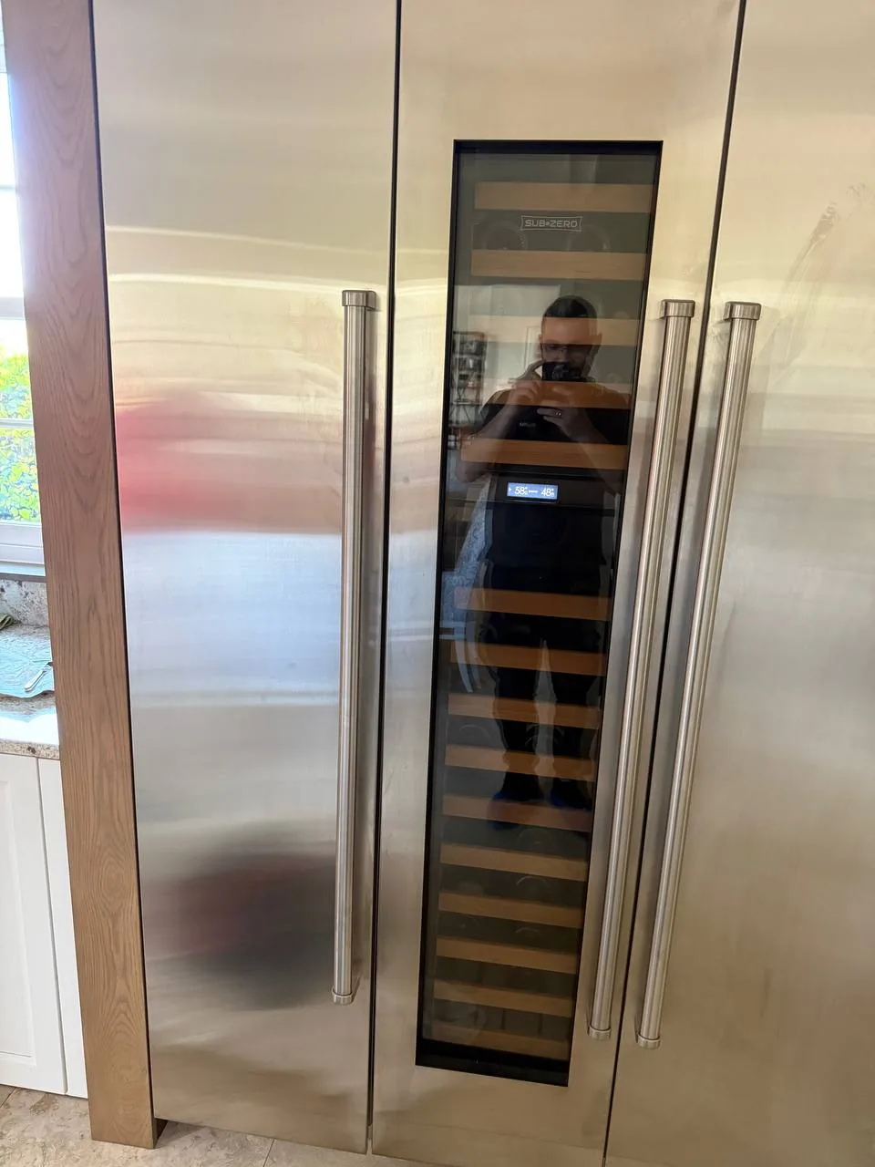 A technician is reflected in the glass door of a Sub-Zero refrigerator