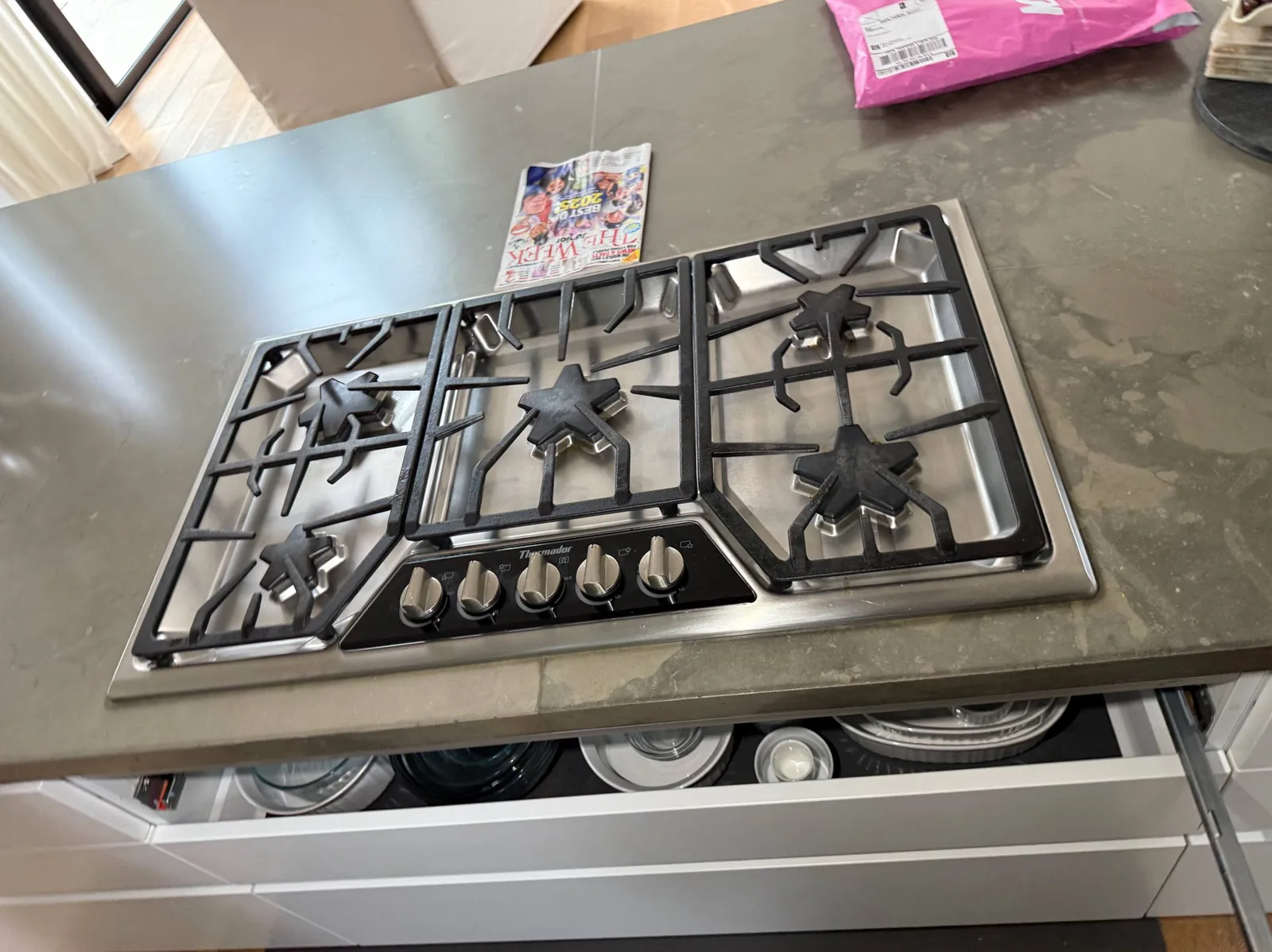 A Thermador cooktop is installed in a grey countertop with a drawer pulled out underneath