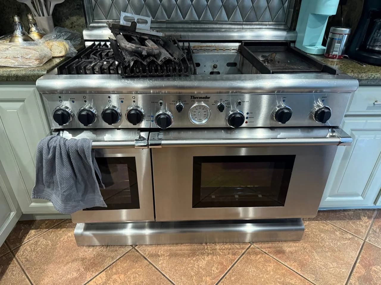 A stainless steel Thermador range with a griddle top and two ovens, with a towel draped over the left oven handle