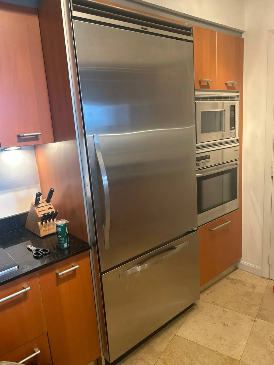 A stainless steel Viking refrigerator with a bottom freezer in a modern kitchen with wood cabinets