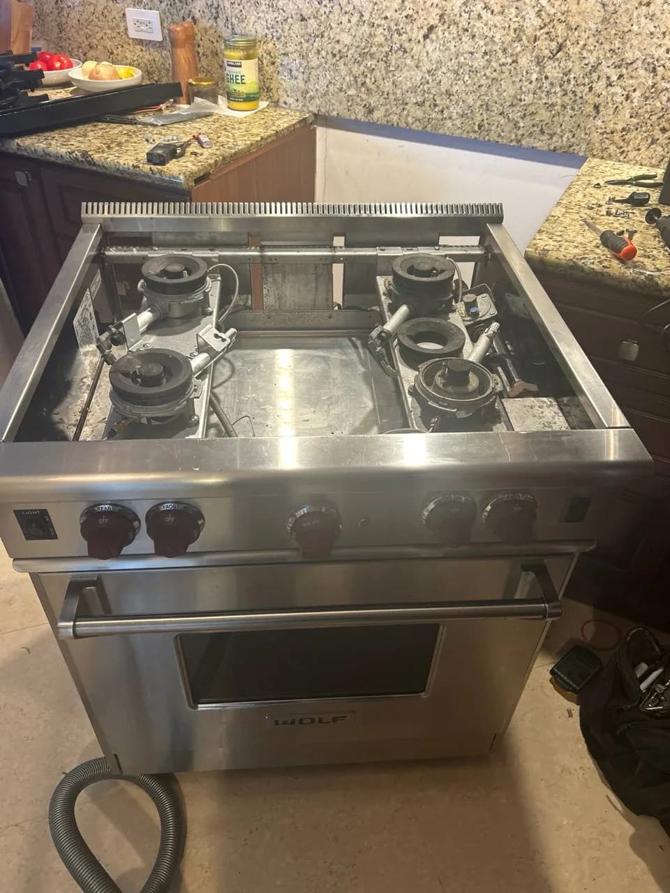 A stainless steel Wolf range oven with the top grates removed, showing the burners